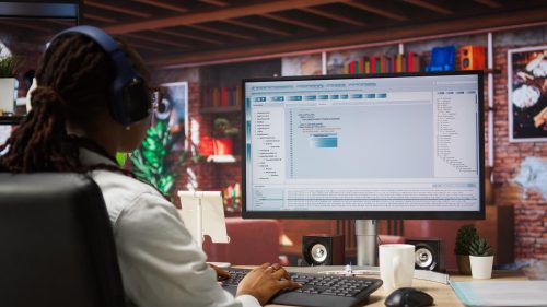 Un programmeur portant des écouteurs tape du code dans un logiciel de